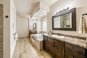 Bathroom with light wood-style floors, two vanities, and a bath