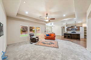 Sitting room featuring arched walkways, a raised ceiling, a ceiling fan, light colored carpet, and recessed lighting