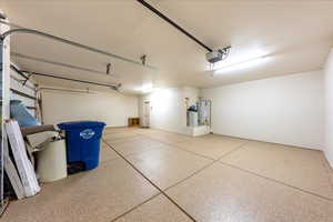 Garage with strapped water heater and a garage door opener