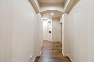 Hallway featuring arched walkways and dark wood-style flooring