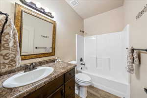 Full bathroom featuring shower / tub combination, light wood-type flooring, vanity, and a textured ceiling