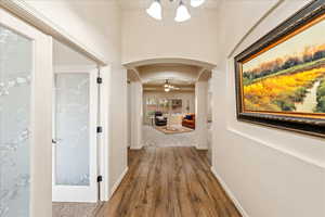 Hall featuring arched walkways and dark wood-style flooring