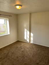 Spare room with a textured ceiling and dark carpet