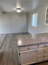 Kitchen with white cabinets, light stone countertops, and light wood-type flooring