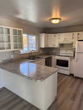 Kitchen featuring white appliances, a peninsula, dark wood-style floors, glass insert cabinets, and a textured ceiling