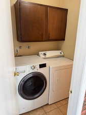 Laundry room with light tile patterned floors, cabinet space, and washer and dryer