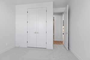 Unfurnished bedroom featuring light colored carpet and a closet
