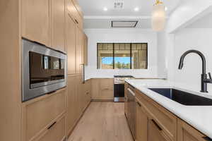 Kitchen featuring light brown cabinetry, light wood-style floors, recessed lighting, hanging light fixtures, and stainless steel appliances