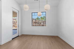 Unfurnished dining area with healthy amount of natural light, light wood finished floors, and vaulted ceiling