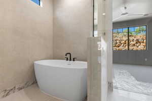 Full bath featuring tile walls, a soaking tub, and a ceiling fan