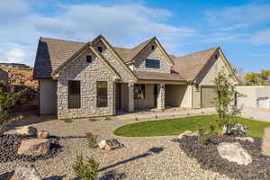 View of front of home with covered porch, stone siding, concrete driveway, and stucco siding