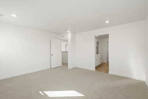 Unfurnished bedroom featuring light colored carpet, recessed lighting, and ensuite bathroom