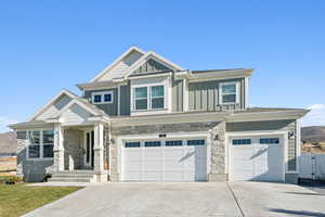 Craftsman house with stone siding, board and batten siding, driveway, and a garage