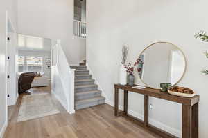 Staircase with wood finished floors and a high ceiling