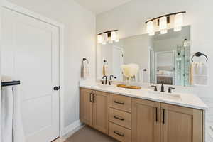 Ensuite bathroom featuring double vanity and baseboards