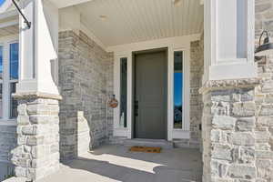 Property entrance featuring stone siding and covered porch