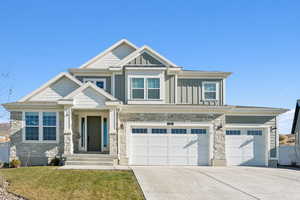 Craftsman-style home featuring stone siding, board and batten siding, concrete driveway, and a 3 car garage