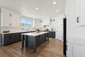 Kitchen featuring glass insert cabinets, white cabinets, light stone counters, recessed lighting, and gray cabinetry
