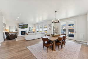 Dining room with a glass covered fireplace, light wood-style flooring, a chandelier, and recessed lighting