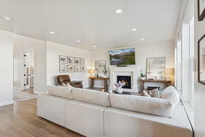 Living area featuring a lit fireplace, recessed lighting, and light wood-style floors