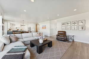 Living room featuring wood-style flooring, recessed lighting, stairs, and a chandelier