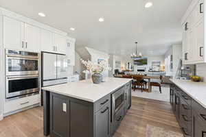 Kitchen with white cabinetry, stainless steel appliances, recessed lighting, light stone counters, and open floor plan