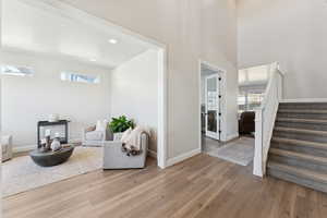 Sitting room with stairs, light wood-style floors, recessed lighting, and a high ceiling