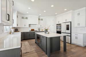 Kitchen featuring gray cabinets, tasteful backsplash, a kitchen breakfast bar, a center island, and recessed lighting