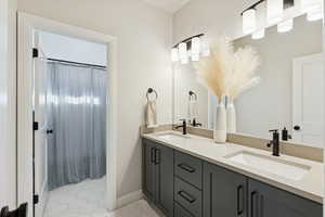 Full bath featuring double vanity, a shower with shower curtain, and light tile patterned floors