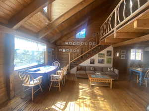 Living room with wooden walls, stairway, wood-type flooring, wooden ceiling, and a skylight