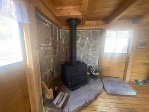 Detailed view of a wood stove, a wood ceiling with exposed beams, and wood finished floors