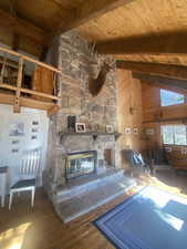 Living room featuring high vaulted ceiling, a fireplace, a wooden ceiling with exposed beams, wood-type flooring, and wooden walls