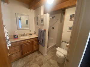 Bathroom featuring vanity, a shower stall, light tile patterned floors, and beamed ceiling