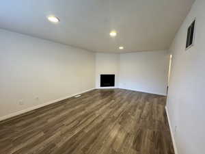 Unfurnished living room with a fireplace, dark wood-style floors, and recessed lighting