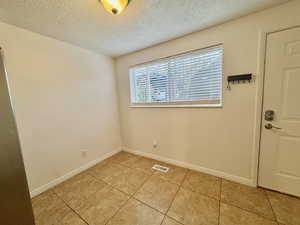 Spare room featuring a textured ceiling and light tile patterned flooring