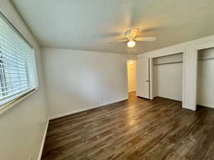 Primary bedroom featuring dark wood finished floors, multiple closets, a ceiling fan, and a textured ceiling