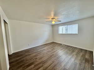 Primary bedroom with dark wood finished floors, a textured ceiling, and a ceiling fan