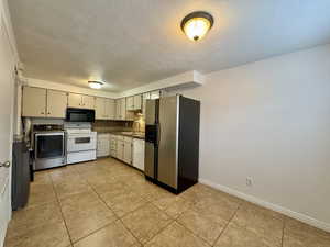 Kitchen featuring white appliances, a textured ceiling, washer / dryer, light tile patterned flooring, and dark countertops