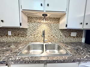 Kitchen with dark countertops, tasteful backsplash, and white cabinets