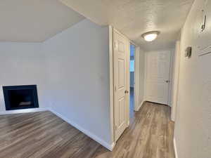 Corridor featuring a textured ceiling and light wood-type flooring