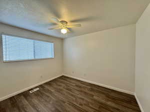 bedroom featuring dark wood-style flooring, a textured ceiling, and a ceiling fan
