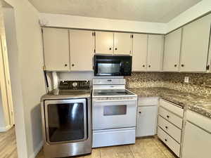 Kitchen featuring white range with electric cooktop, washer / clothes dryer, black microwave, decorative backsplash, and a textured ceiling