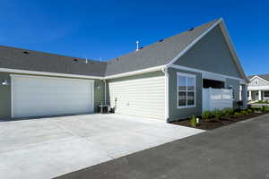 View of side of property with driveway, roof with shingles, and an attached garage