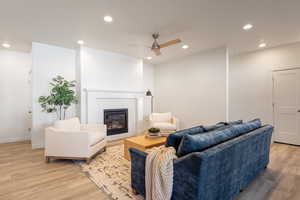 Living room with recessed lighting, light wood-type flooring, a brick fireplace, and ceiling fan