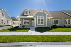 View of front of property featuring a porch, a front lawn, roof with shingles, and board and batten siding
