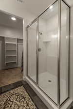 Bathroom featuring a walk in closet, a shower stall, and recessed lighting