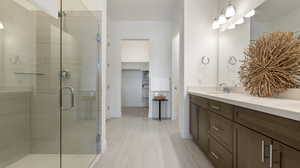 Full bathroom with double vanity, a walk in closet, a shower stall, and light tile patterned flooring