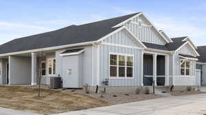 View of front of home with board and batten siding, roof with shingles, driveway, and a porch