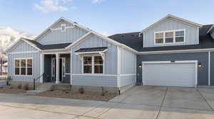 View of front facade featuring board and batten siding, a shingled roof, driveway, and a garage