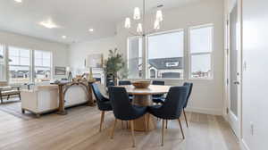 Dining space with light wood finished floors, a chandelier, and recessed lighting